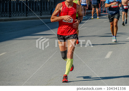 male runner athlete in compression socks and knee pads running marathon race, sports summer games 104341336