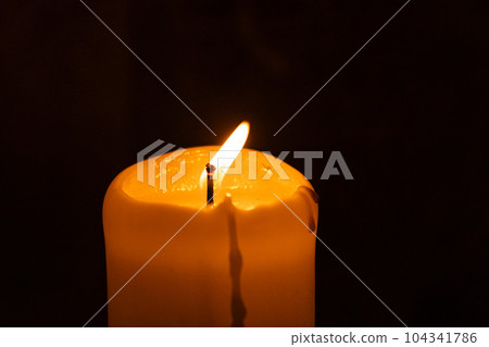A lonely burning candle in an old temple against the background of a wall 104341786