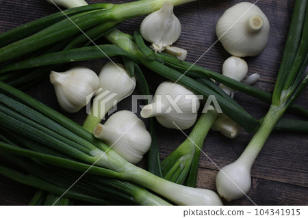 Fresh garlic and onions on the table. Kitchen still life with heads of garlic. Vegetables ingredients for a recipe on a kitchen board Fresh garlic and onions on the table. Kitchen still life with heads of garlic. Vegetables ingredients for a recipe on a kitchen board 104341915