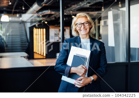 Happy smiling 50's confident mature businesswoman looking at camera, middle-aged experienced senior female professional hired by company on first day at work, happy new employee on office background 104342225