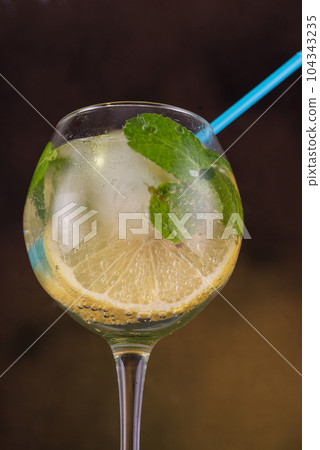 Macro photo of a wine glass with lemon and mint. A straw in a wine glass. 104343235