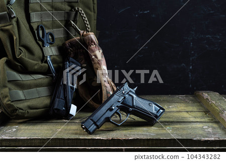 Pistol and paramedic tools. Military doctor. A pistol and a backpack on a military crate. 104343282