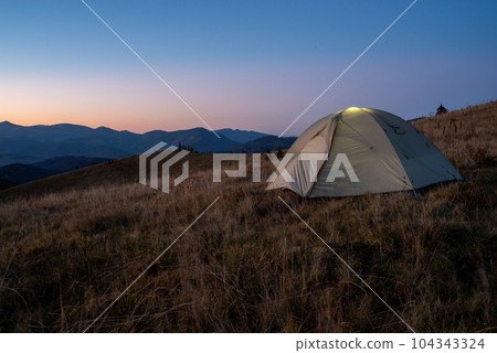 A tourist tent stands on top of a mountain. Camping at the top of the mountain. 104343324