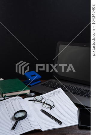 Office in the office. A ballpoint pen lying on a journal. Documentation and laptop. 104343408
