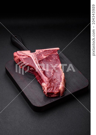 Raw juicy beef t-bone steak with salt, spices and herbs Raw juicy beef t-bone steak with salt, spices and herbs 104343989