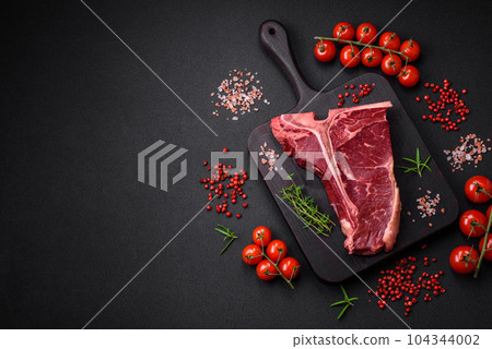 Raw juicy beef t-bone steak with salt, spices and herbs 104344002