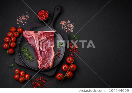 Raw juicy beef t-bone steak with salt, spices and herbs Raw juicy beef t-bone steak with salt, spices and herbs 104344009
