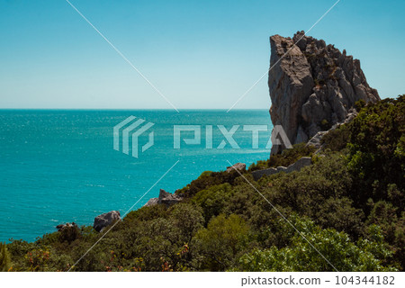 A high sheer cliff, beautiful blue sea and sky. 104344182