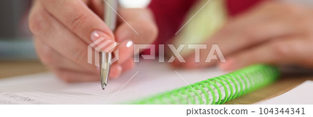 Female hand holding pen and write something in notepad 104344341