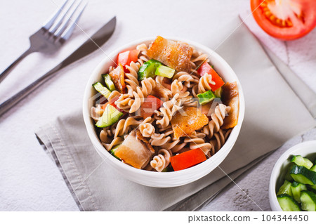 Fresh salad of buckwheat pasta, tomatoes, cucumbers and fried bacon in a bowl Fresh salad of buckwheat pasta, tomatoes, cucumbers and fried bacon in a bowl 104344450