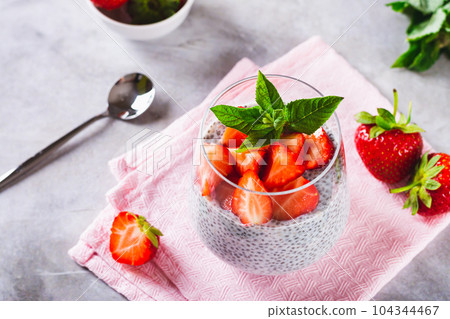 Fresh chia seeds with milk, fresh strawberries and mint in a glass on the table Fresh chia seeds with milk, fresh strawberries and mint in a glass on the table 104344467