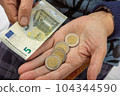 An old woman counts euro coins on her palm 104344590