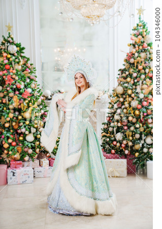 Snow Maiden in a costume with a kokoshnik in a room with christmas tree 104346000