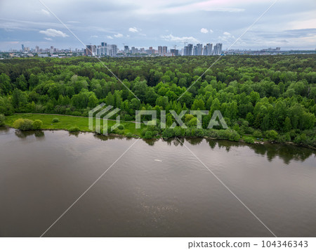 Big lake with green shores in bright sun light and city on horizon, aerial landscape. Recreation concept. Aerial view Big lake with green shores in bright sun light and city on horizon, aerial landscape. Recreation concept. Aerial view 104346343
