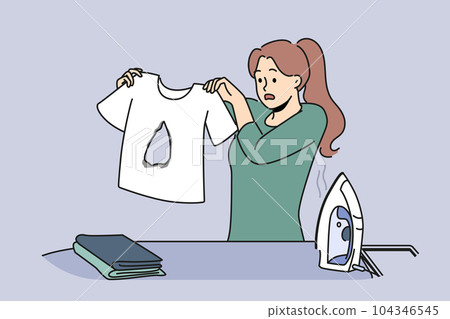 Clumsy housewife ironing clothes burnt hole in t-shirt and doesn know how to fix mistake Clumsy housewife ironing clothes burnt hole in t-shirt and doesn know how to fix mistake 104346545