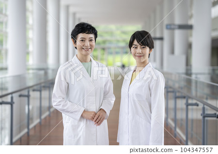 Two women in white coat looking at camera portrait 104347557