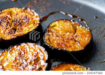 在煎鍋中烤圓形茄子片的烹飪場景(塔雷燒)。 在煎鍋中烤圓形茄子片的烹飪場景(塔雷燒)。 104347560