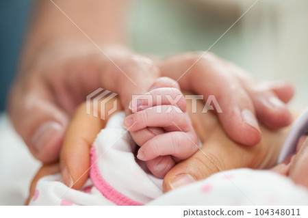 Closeup of a newborn and her parents hands at hospital on the day of her birth. Family concept. Parenthood concept 104348011