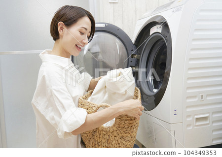 Dollar age woman doing laundry in washing machine Dollar age woman doing laundry in washing machine 104349353