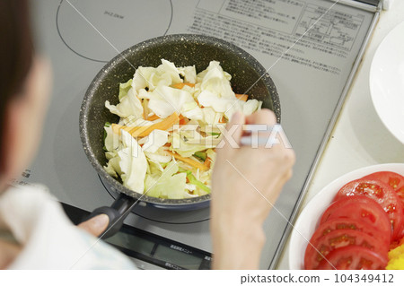 Close-up of stir-fried vegetables being fried by a woman 104349412