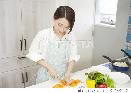 中年婦女在廚房切胡蘿蔔 中年婦女在廚房切胡蘿蔔 104349442