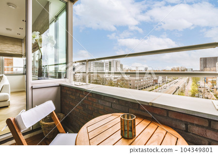 a balcony with chairs, tables and a view of the city from it's window sid on a sunny day 104349801