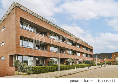 a brick building with windows and bales on the top, in front of it is an empty parking area a brick building with windows and bales on the top, in front of it is an empty parking area 104349811