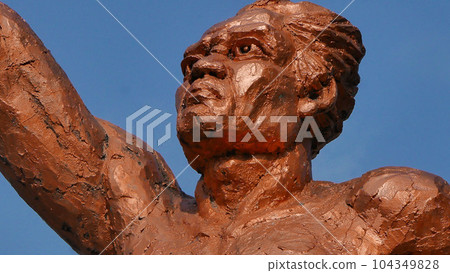 Statue of spirit of sport in a form of man holding torch against blue sky, Patung obor manahan located at the Manahan stadium Surakarta  104349828