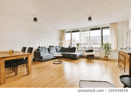 a living room with wood flooring and white walls, including a wooden dining table surrounded by black leather chairs a living room with wood flooring and white walls, including a wooden dining table surrounded by black leather chairs 104349859