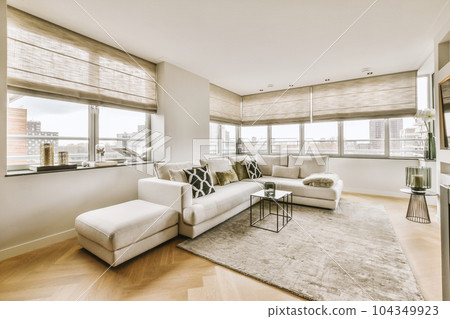 a living room with hardwood flooring and white couches in front of large windows looking out onto the city a living room with hardwood flooring and white couches in front of large windows looking out onto the city 104349923