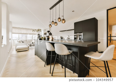 a kitchen and dining area in a modern apartment with white walls, hardwood flooring and black cabinetry on the island a kitchen and dining area in a modern apartment with white walls, hardwood flooring and black cabinetry on the island 104349957