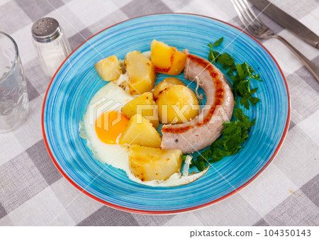 Dinner of scrambled eggs with sausages and potatoes 104350143