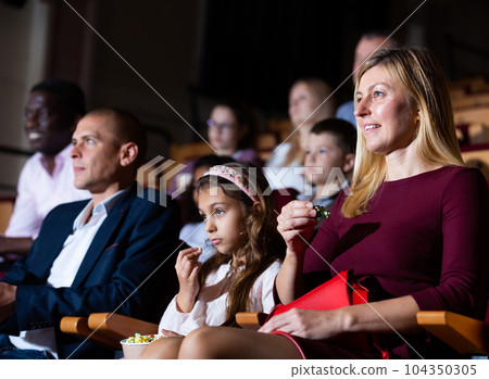 Woman with family watching movie in picture theater Woman with family watching movie in picture theater 104350305