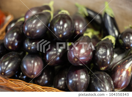 Pile of fresh purple aubergines at farmers market stall 104350343