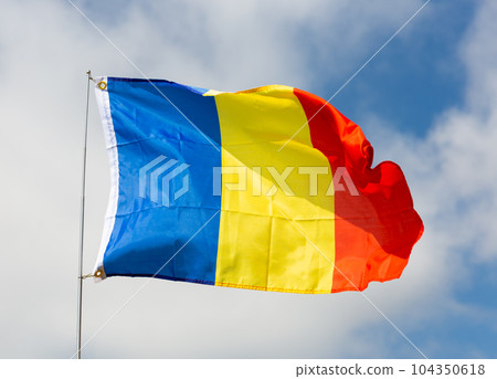 Flag of state of Romania flutters against blue sky 104350618