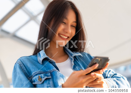 Young asian woman smiling using mobile smart phone outdoor Young asian woman smiling using mobile smart phone outdoor 104350958