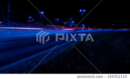 Lights of cars at night. Street line lights. Night highway city. Long exposure photograph night road. Colored bands of red light trails on the road. Background wallpaper defocused  104352134