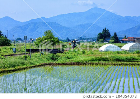 Tadami Line train Kiha E120 running through the countryside of Aizu Basin (Aizumisato Town, Fukushima Prefecture, early June morning) 104354378