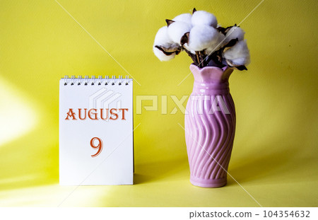Calendar with text 9 august on yellow background and with a vase of flowers Calendar with text 9 august on yellow background and with a vase of flowers 104354632