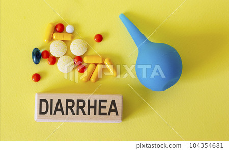 Text diarrhea on a wooden block and enema, pills on a light background Text diarrhea on a wooden block and enema, pills on a light background 104354681