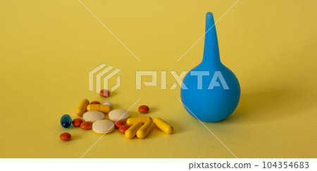 On a yellow background, an enema and pills for diarrhea 104354683