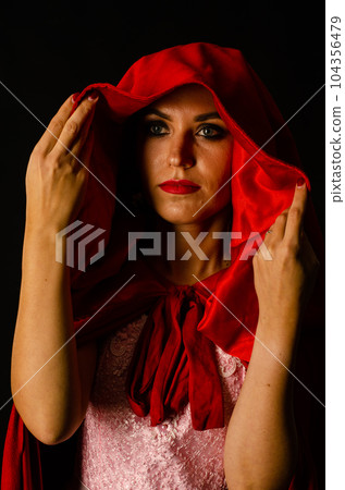 beautiful woman red cloak with red flowers roses in studio. Woman Red Riding Hood. Dramatic and fantastic shooting,fashionable toning. Like a princess 104356479