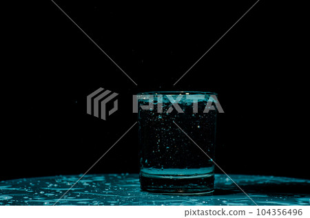 Isolated shot of water splashing from ice cubes being dropped in a glass. 104356496