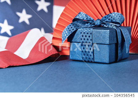 Blue Gift box against US American flag. Happy Independence Day. Stars and stripes. Copy space. memorial day Blue Gift box against US American flag. Happy Independence Day. Stars and stripes. Copy space. memorial day 104356545