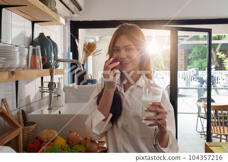 Portrait of a young cheerful asian woman at kitchen room with healthy raw food. Vegetarianism, wellbeing and healthy lifestyle concept Portrait of a young cheerful asian woman at kitchen room with healthy raw food. Vegetarianism, wellbeing and healthy lifestyle concept 104357216