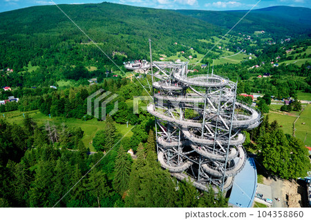 Sky Walk observation tower in Sweradow Zdroj, Poland. Tourist attraction in montains, aerial view. Panoramic view of nature landscape with green forest Sky Walk observation tower in Sweradow Zdroj, Poland. Tourist attraction in montains, aerial view. Panoramic view of nature landscape with green forest 104358860