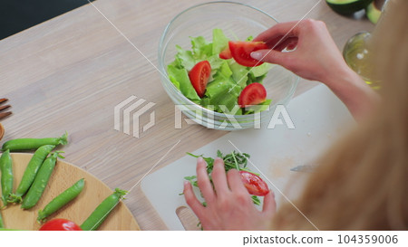 Top view of young girl in the process of preparing healthy food. Preparation of fresh vegetable salad. Healthy eating and cooking concept. Top view of young girl in the process of preparing healthy food. Preparation of fresh vegetable salad. Healthy eating and cooking concept. 104359006