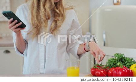 Young girl cooking healthy food salad using mobile cookbook apps in home kitchen. Healthcare concept. Organic fresh fruit. Young girl cooking healthy food salad using mobile cookbook apps in home kitchen. Healthcare concept. Organic fresh fruit. 104359218