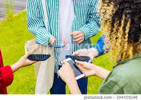 Multinational youth group showing smartphones to each other 104359246