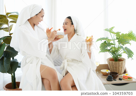 Asia women friends relaxing enjoy and spa massage with facial masks  tomato put on bathrobe.  104359703